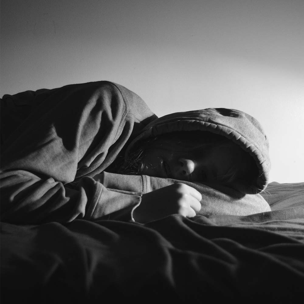 Imagen en blanco y negro de una mujer acurrucada en su cama